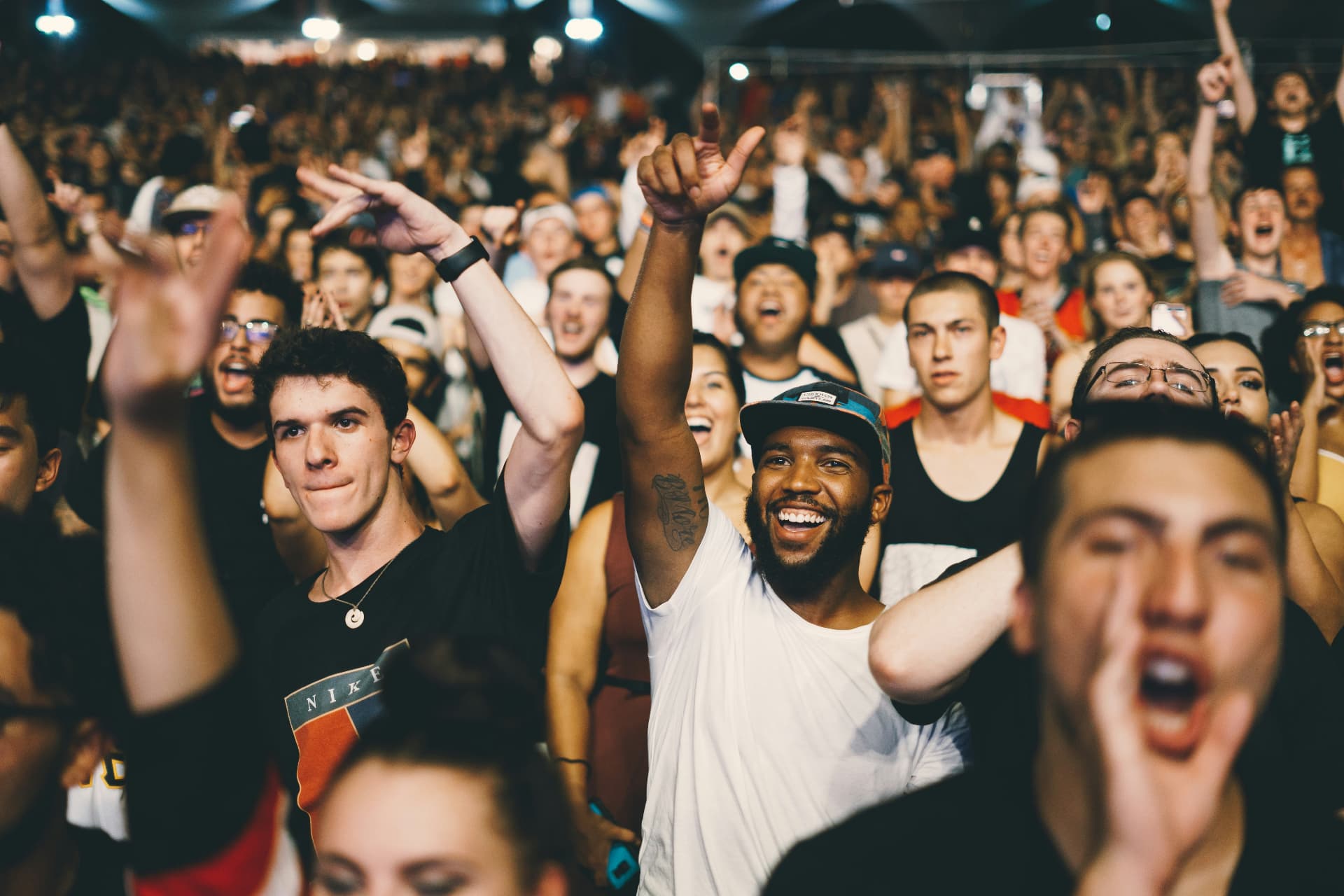 A packed crowd with arms raised, cheering together at a community celebration
