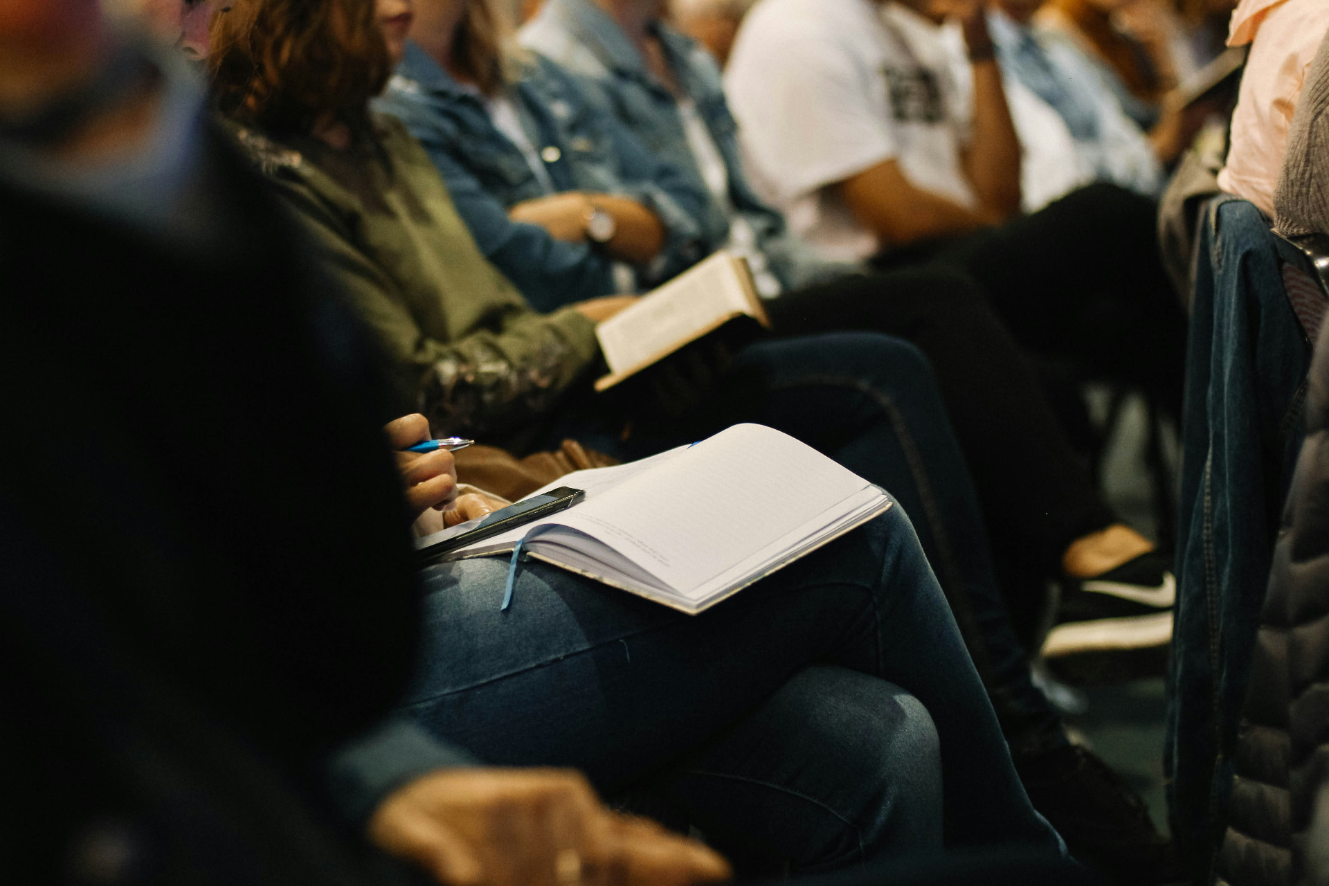 People seated in rows taking notes in an open notebook during a workshop